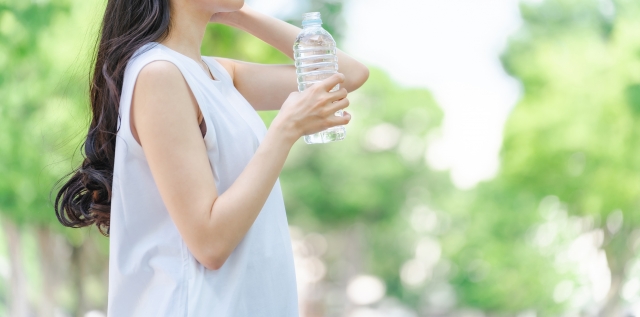 夏にペットボトルを持って立っている女性